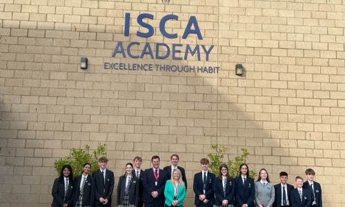 Students from Isca outside the school in front of the Isca School logo with Headteacher and Steve Race MP