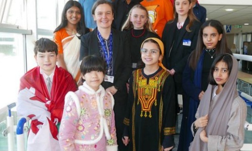 Students from St James stood on stairs wearing traditional or cultural dress