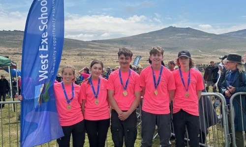 West Exe Team stood with flags either side of them at the finish of the Ten Tors