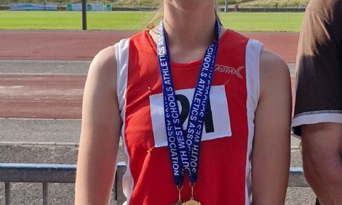 Sophia stood at running track with medals around her neck. 