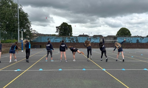 Honiton girls outside on court practicing cricket drills 