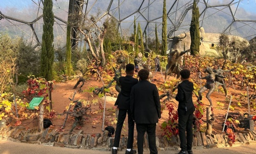 Three students in uniform examining plants