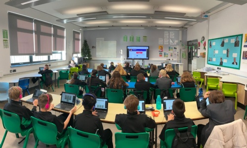 Rows of students sat at desks with computers