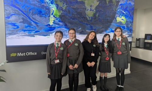 Cranrbook Students stood infront of a world map background visisting the Met Office