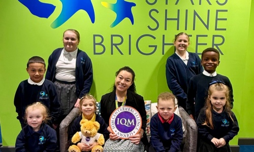 A staff memebr and students sat with the IQM Award