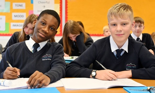 Two students sat at their desk looking at the camera